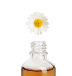 Essential oil dripping from chamomile petal into glass bottle on white background