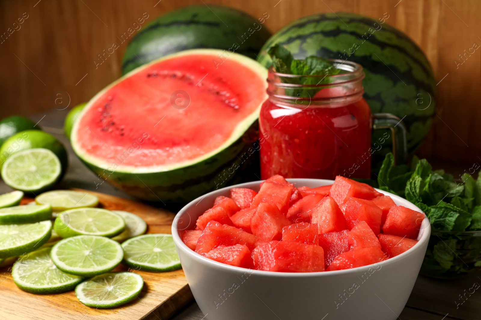 Photo of Fresh watermelon drink with lime and ingredients on wooden table, closeup