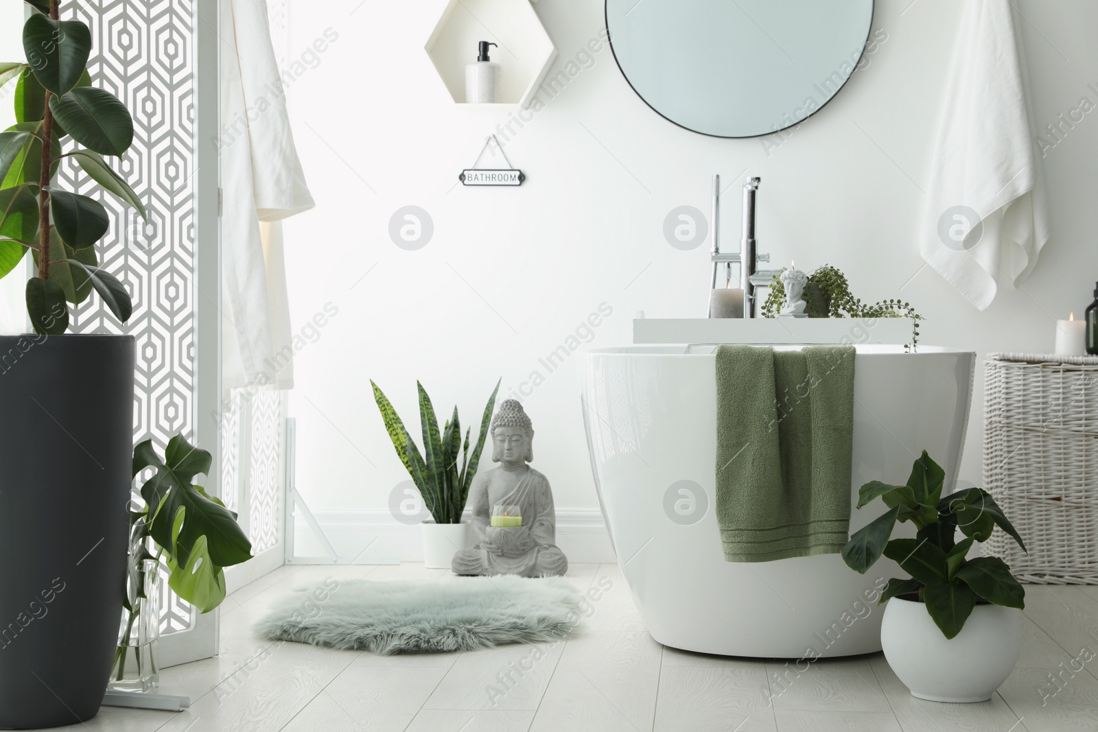 Photo of Stylish bathroom interior with modern tub, houseplants and beautiful decor. Home design