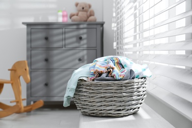Photo of Wicker laundry basket with different clothes on window sill indoors