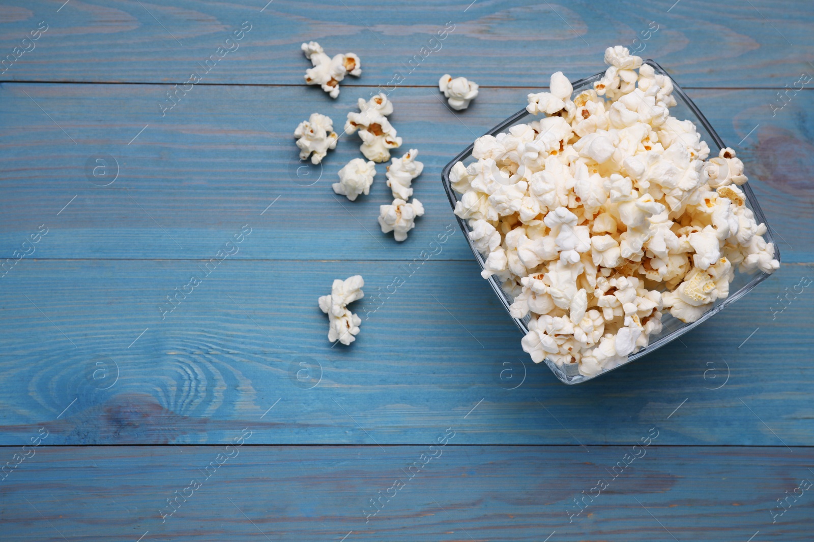 Photo of Tasty popcorn on light blue wooden table, flat lay. Space for text