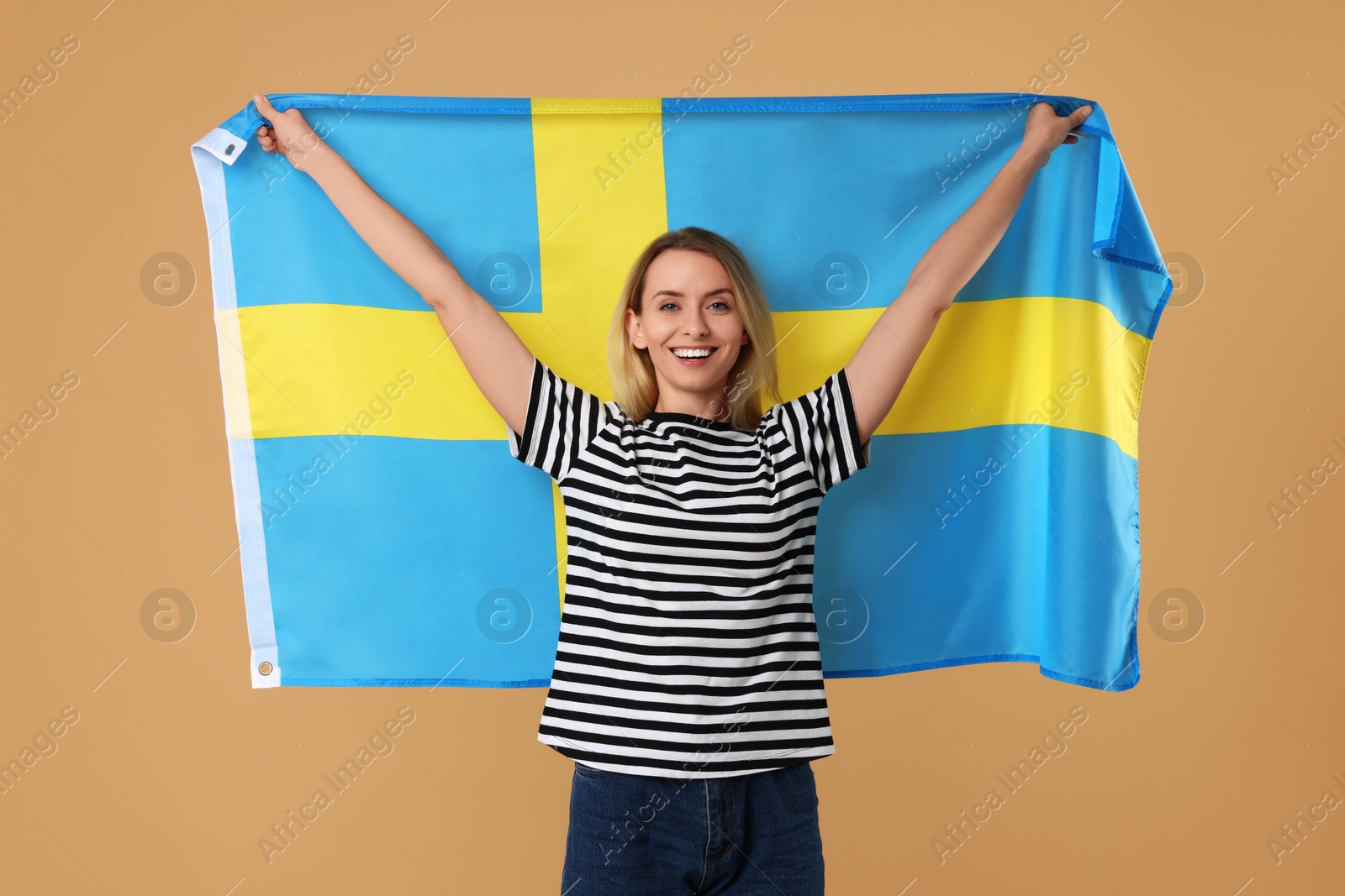 Photo of Happy woman with flag of Sweden on beige background