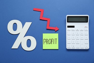 Photo of Sticky note with word Profit, calculator, percent symbol and up arrow on blue background, flat lay