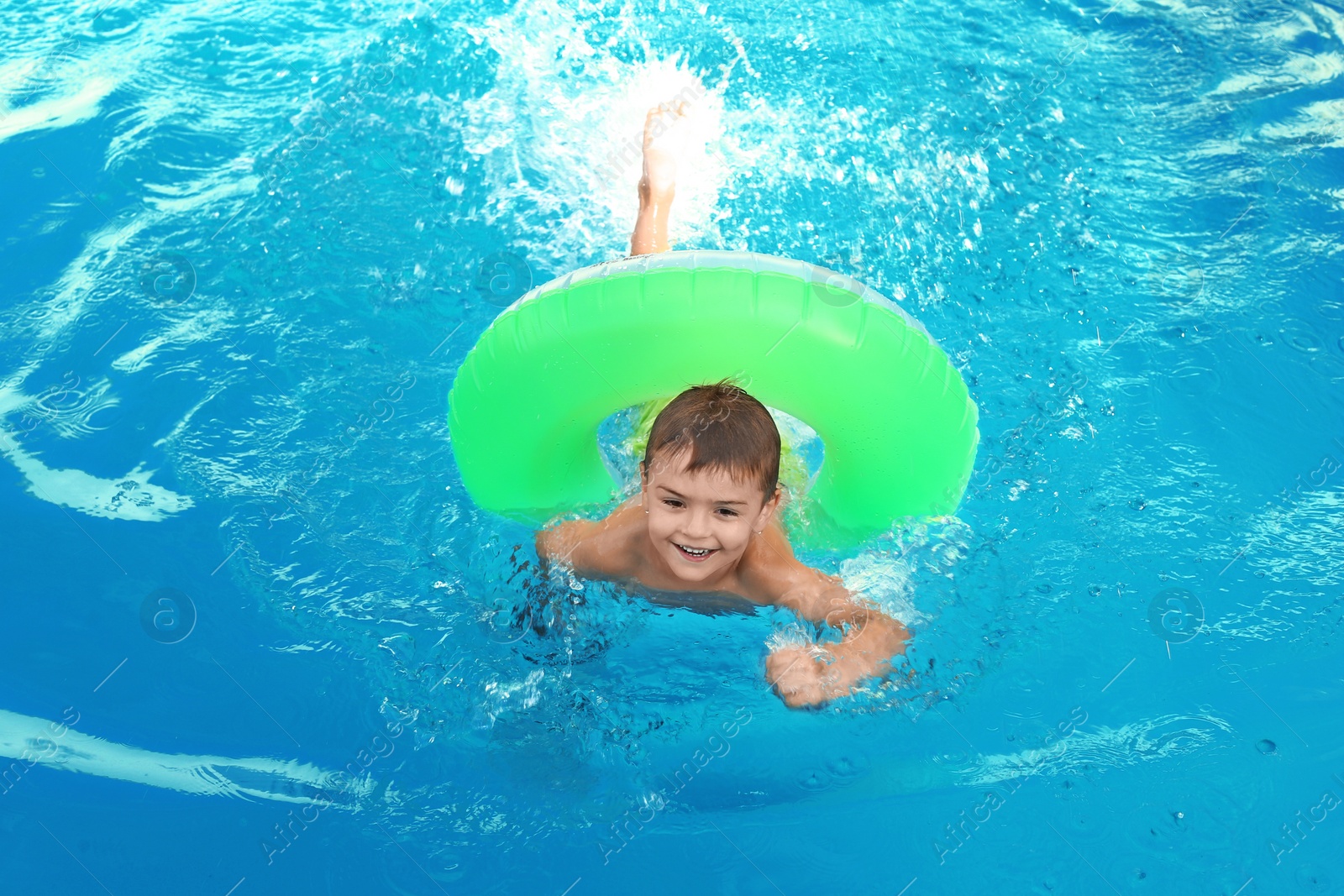 Photo of Little child with inflatable ring in outdoor swimming pool. Dangerous situation