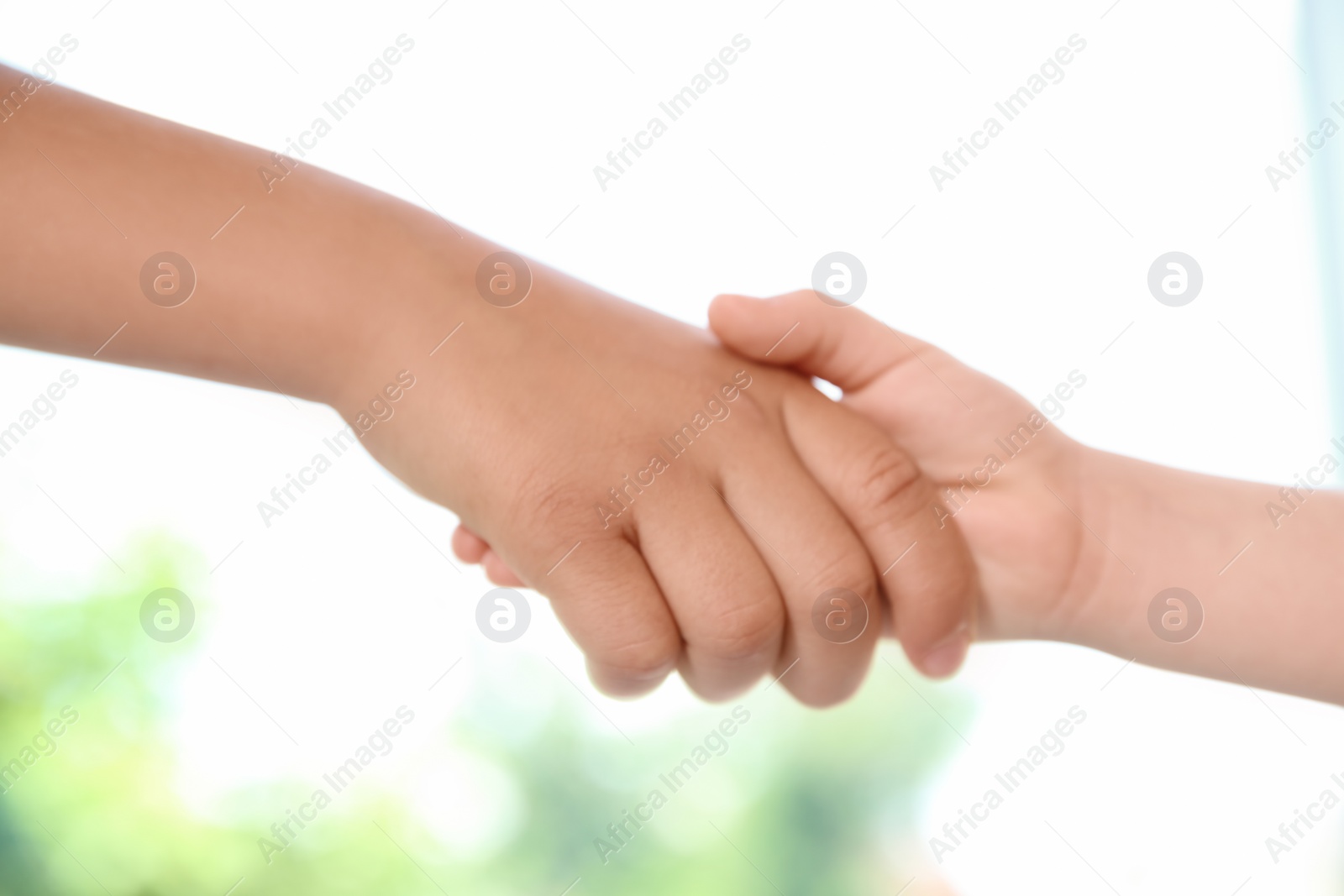 Photo of Children holding hands on blurred background, closeup. Unity concept