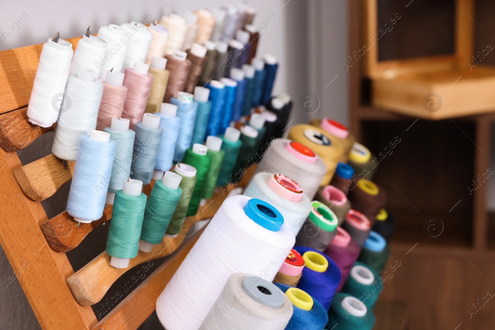 Photo of Set of colorful threads on stand in tailor studio, closeup. Space for text