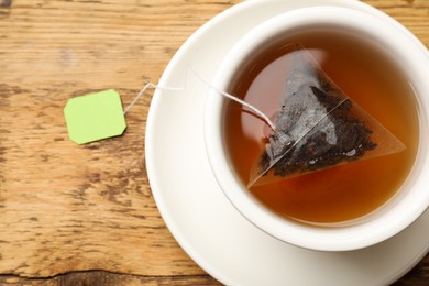 Photo of Tea bag in cup on wooden table, top view