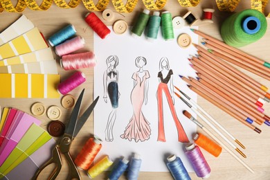 Photo of Sketch of fashion clothes and thread supplies at designer's workplace, flat lay