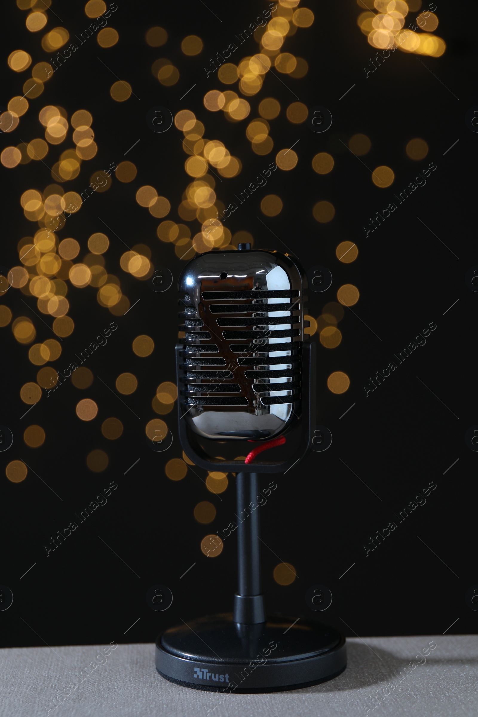 Photo of Vintage microphone on table against black background with blurred lights. Sound recording and reinforcement