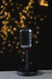 Vintage microphone on table against black background with blurred lights. Sound recording and reinforcement