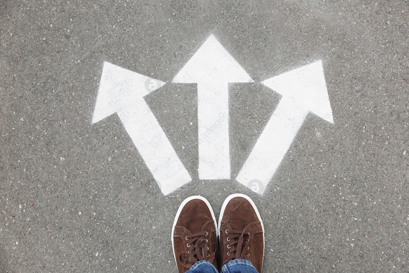 Photo of Woman standing near arrows on asphalt, top view. Choice concept