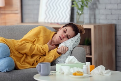 Photo of Sick woman suffering from cold on sofa at home