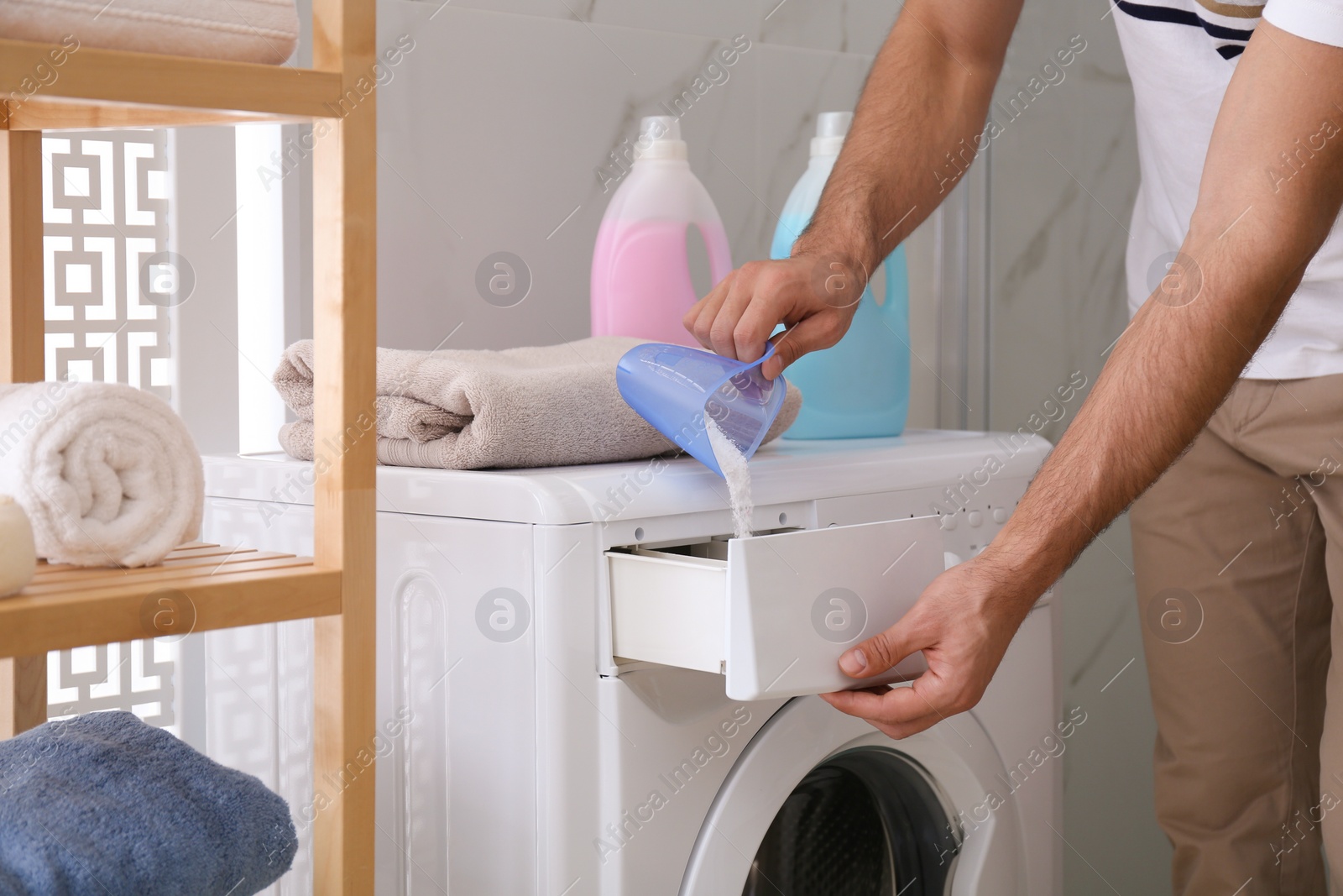 Photo of Man pouring laundry detergent into washing machine drawer in bathroom, closeup