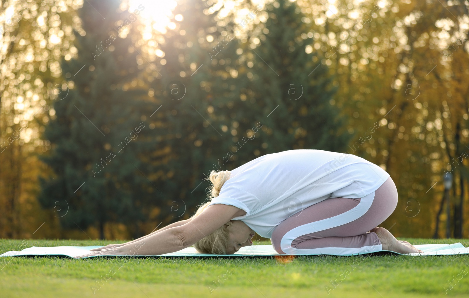 Photo of Happy mature woman practicing yoga in park. Active lifestyle