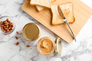 Jar with creamy peanut butter and toasts on table