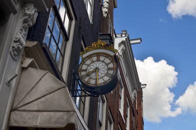 Beautiful building facade with vintage clock against blue sky, low angle view. Space for text