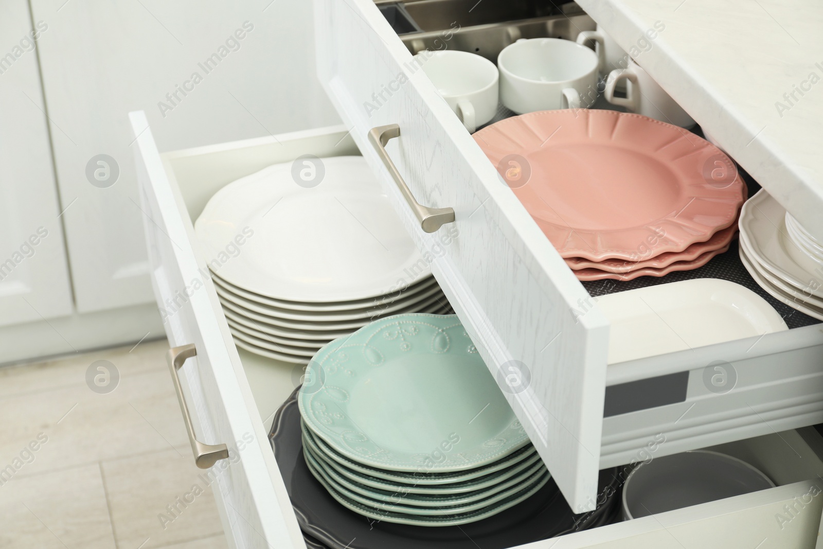 Photo of Clean plates and bowls in drawers indoors