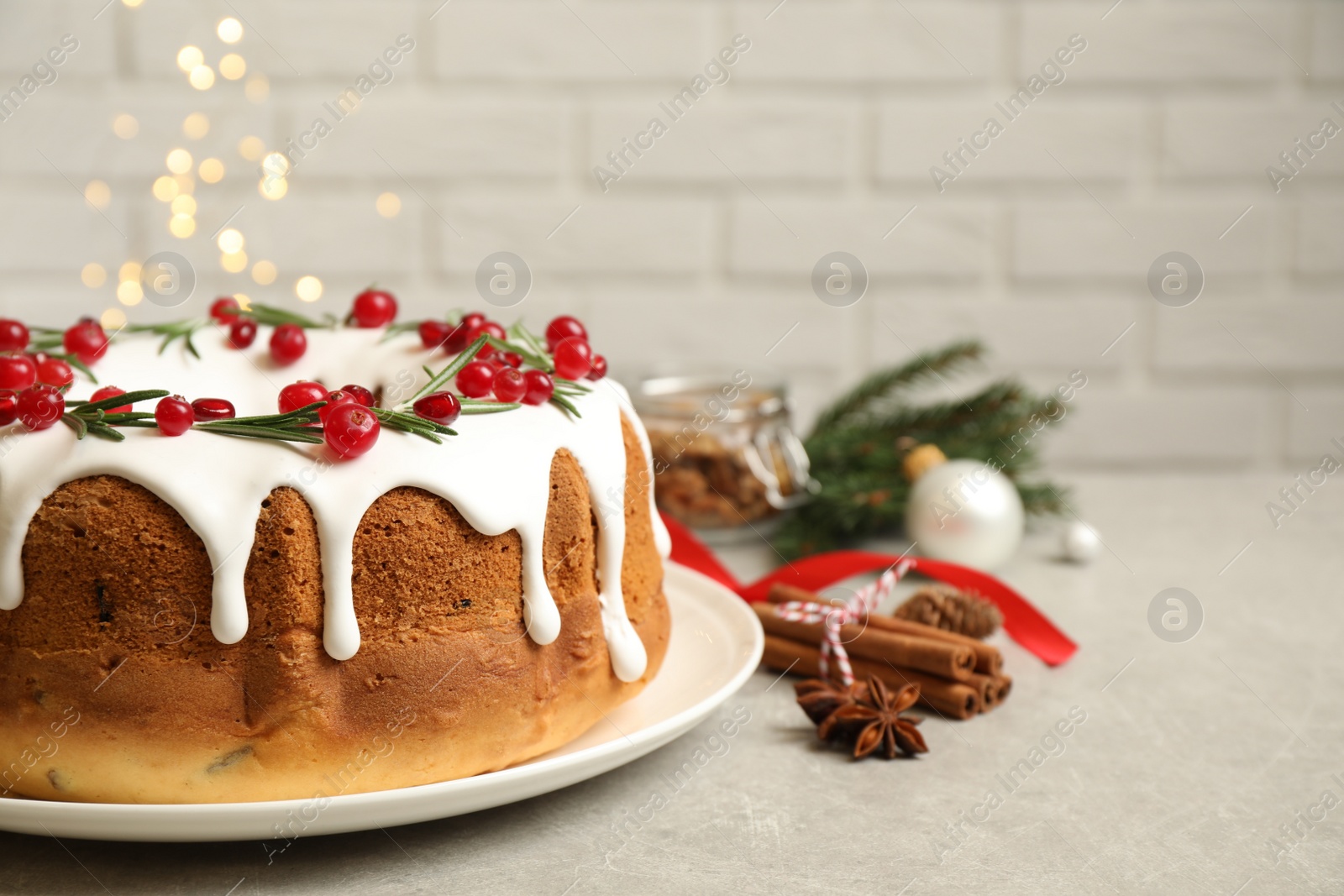 Photo of Traditional Christmas cake with cranberries, pomegranate seeds and rosemary on light grey table, space for text