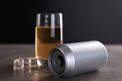 Aluminium can, energy drink in glass and ice cubes on grey table, selective focus