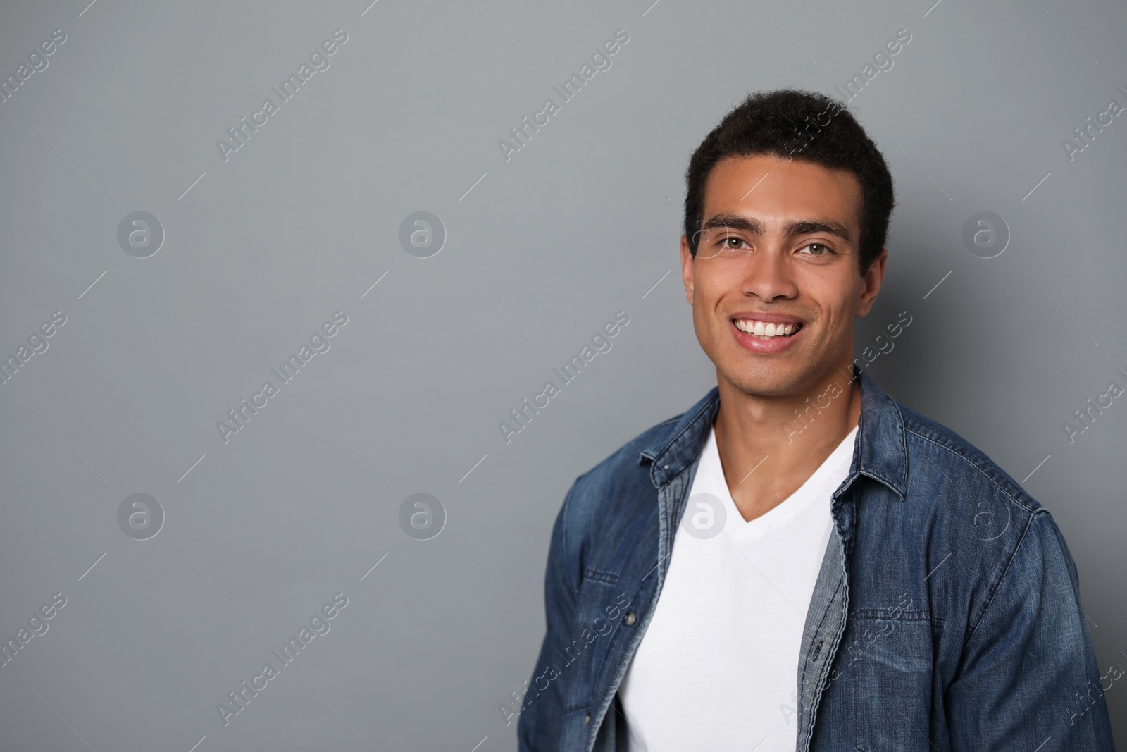 Photo of Handsome young African-American man on grey background. Space for text