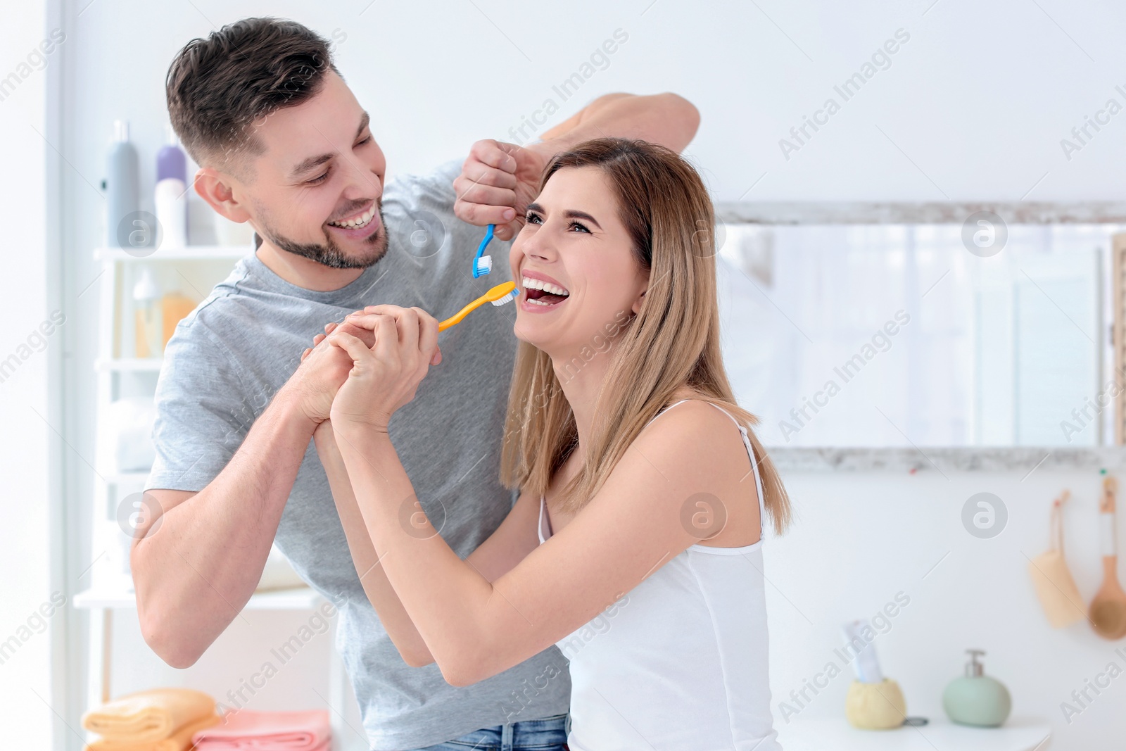 Photo of Young couple brushing teeth together in bathroom