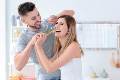 Photo of Young couple brushing teeth together in bathroom