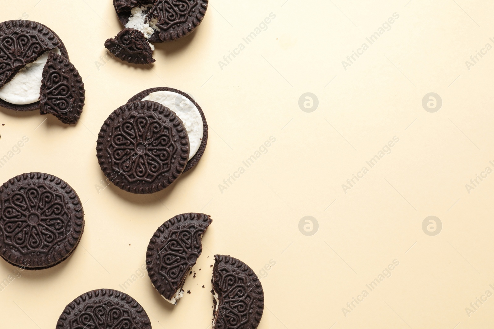 Photo of Tasty chocolate cookies with cream on color background, flat lay. Space for text