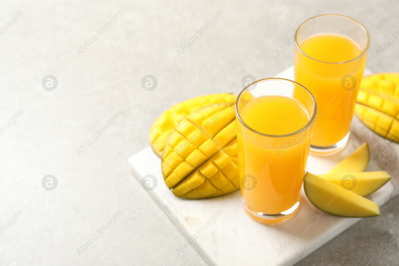 Photo of Fresh mango drink and cut fruits on table. Space for text