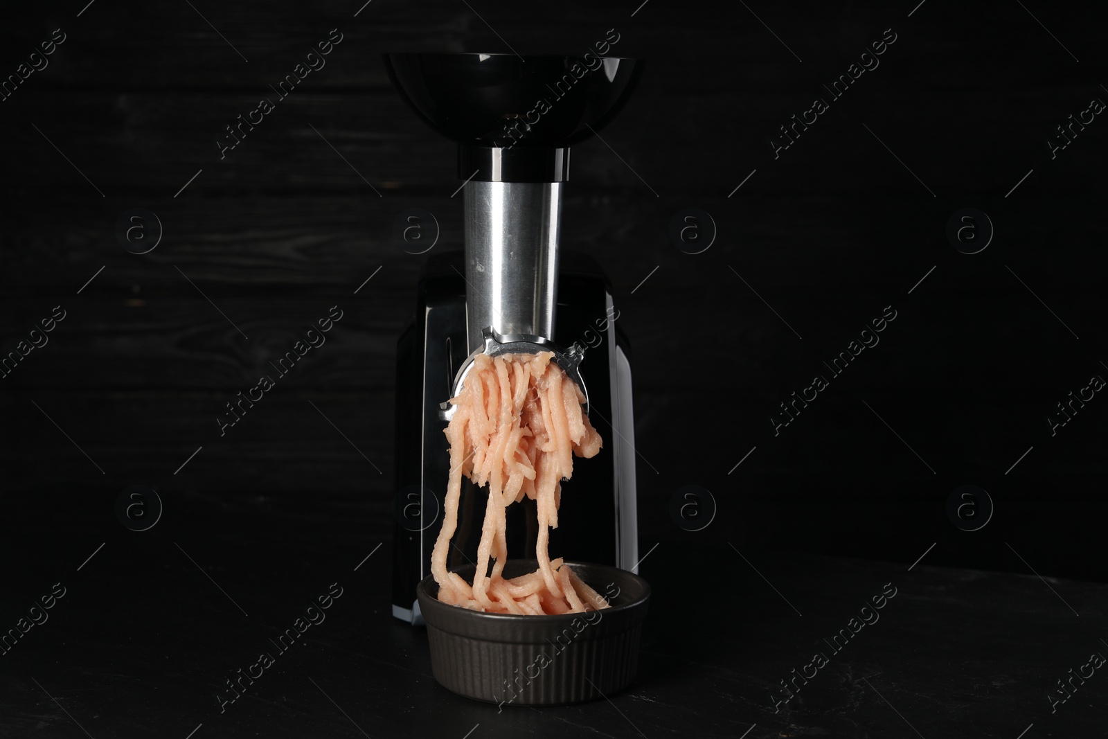 Photo of Electric meat grinder with chicken mince on black table