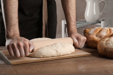 Photo of Male baker preparing bread dough at table, closeup