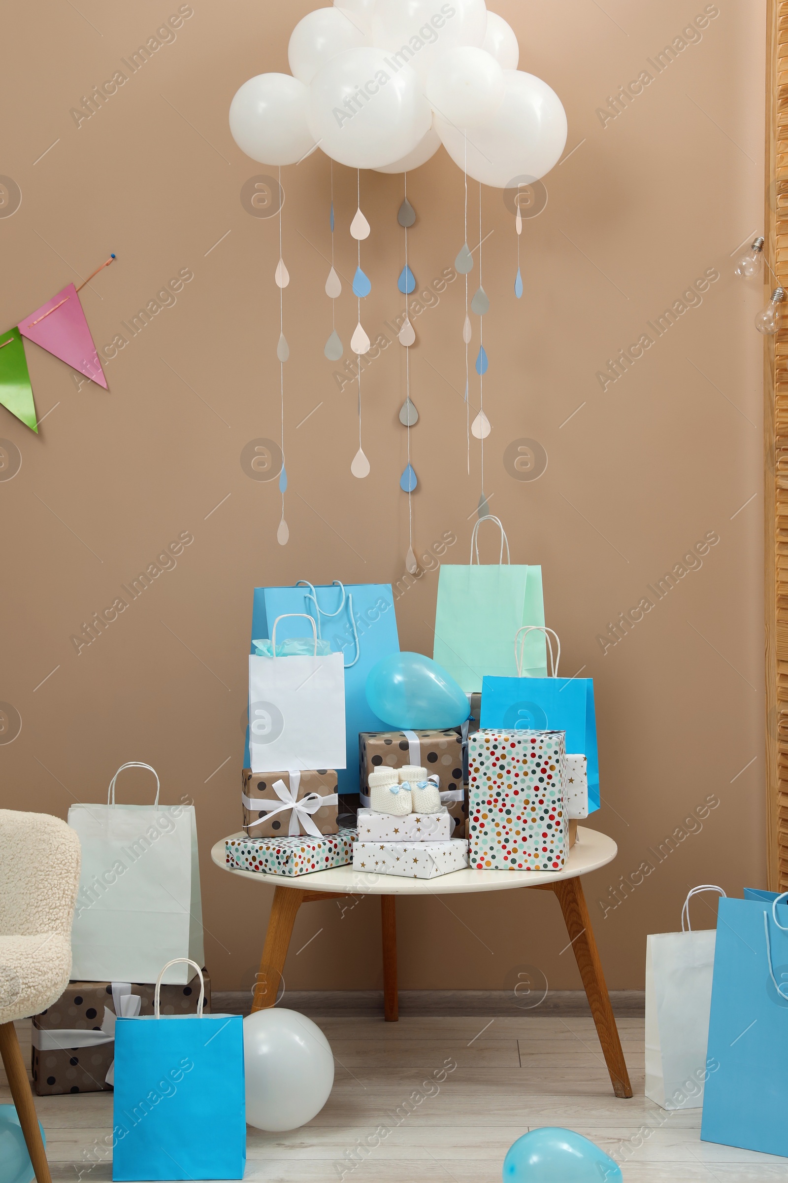 Photo of Baby shower party. Festive decor, gift boxes and bags in stylish room