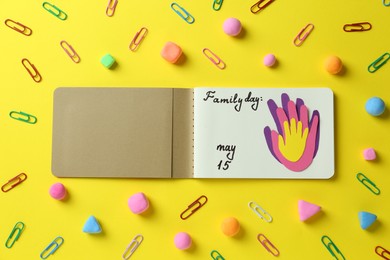 Photo of Happy Family Day. Flat lay composition with notebook on yellow background