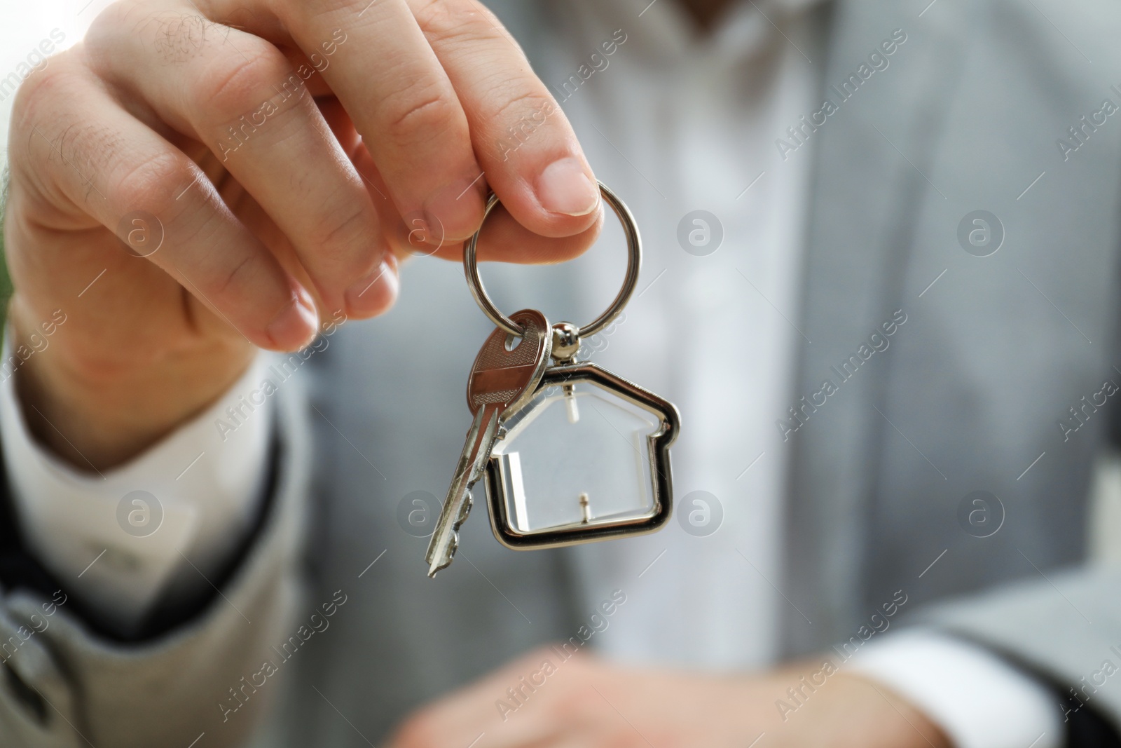 Photo of Real estate agent holding house key with trinket, closeup