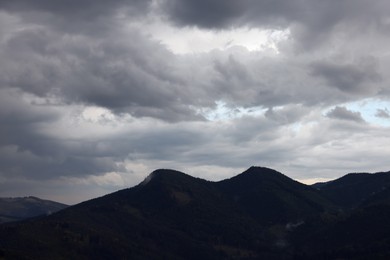 Photo of View of sky with grey thunder clouds over mountains
