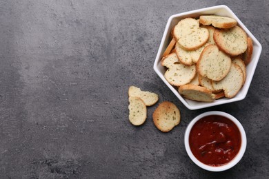 Photo of Crispy rusks and dip sauce on grey table, flat lay. Space for text