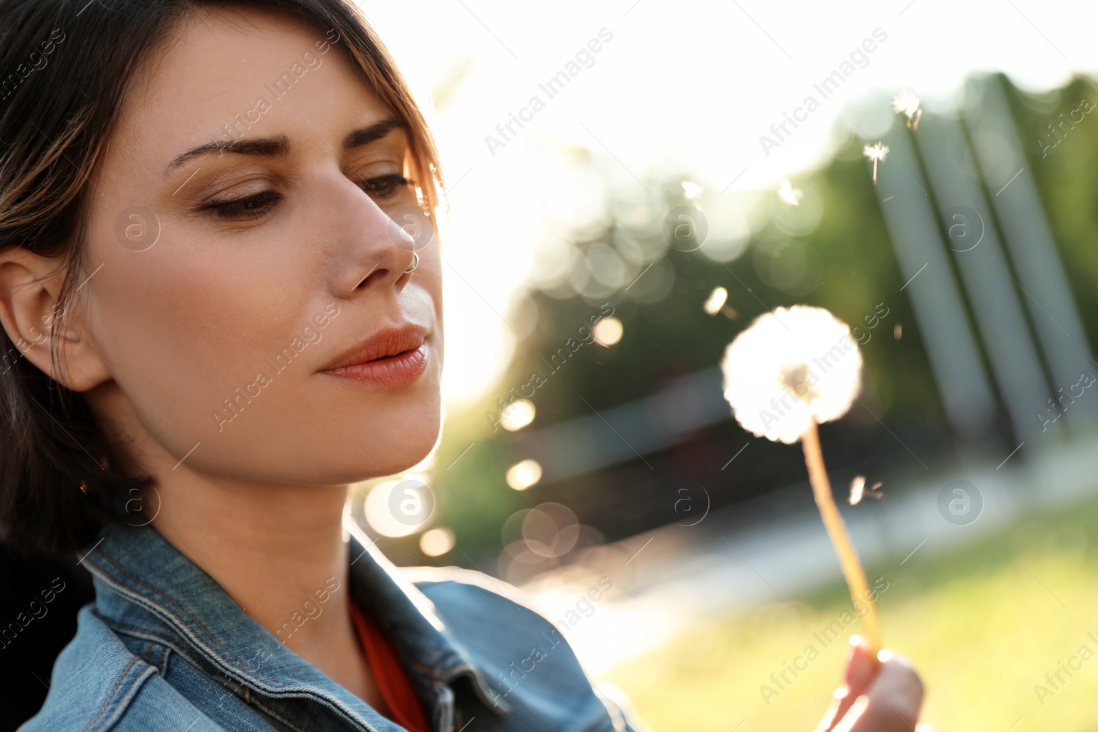 Photo of Young woman with dandelion in park on sunny day. Allergy free concept