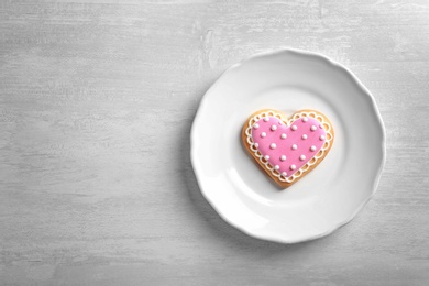 Photo of Plate with decorated heart shaped cookie and space for text on table, top view