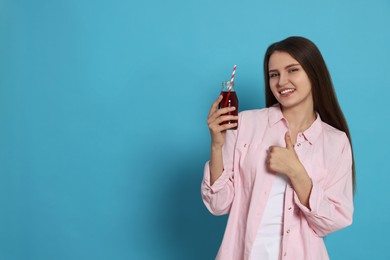 Photo of Beautiful young woman with glass bottle of juice on light blue background. Space for text