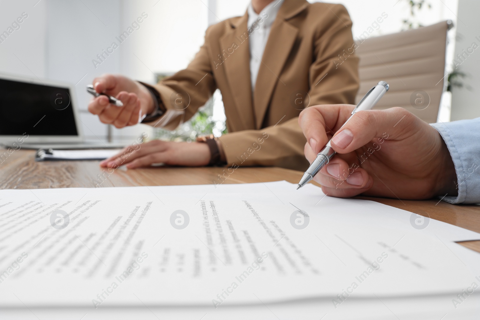 Photo of Businesspeople signing contract at table in office, closeup