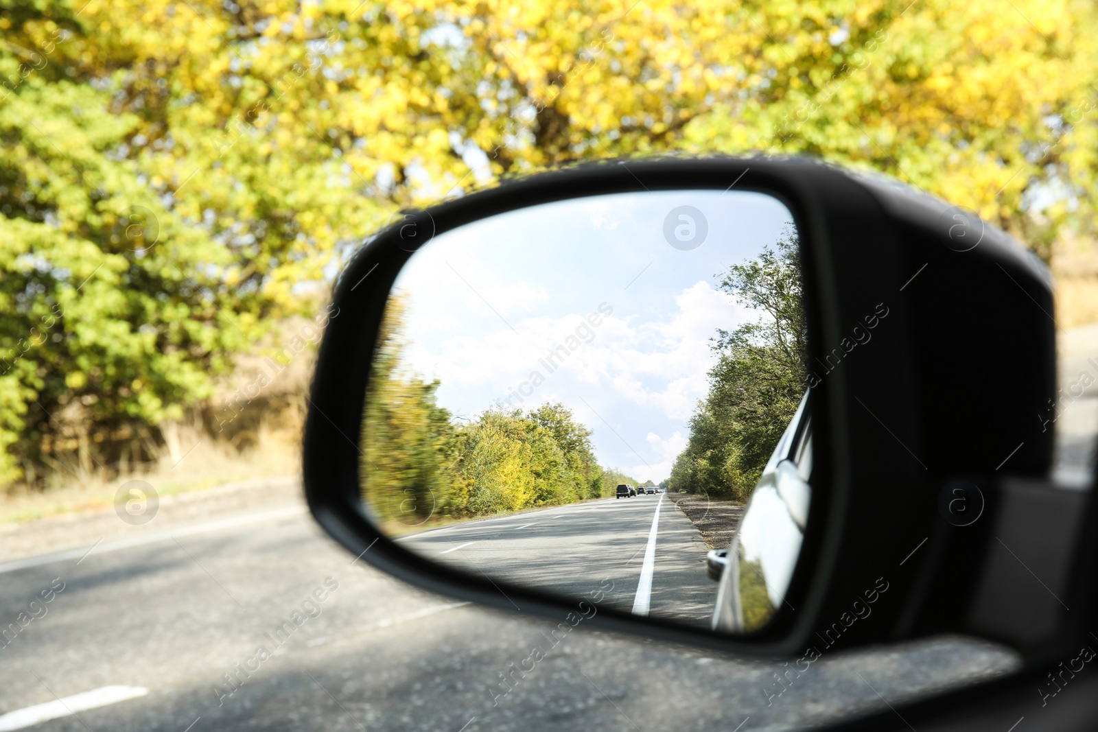 Photo of Closeup of car side rear view mirror on sunny day