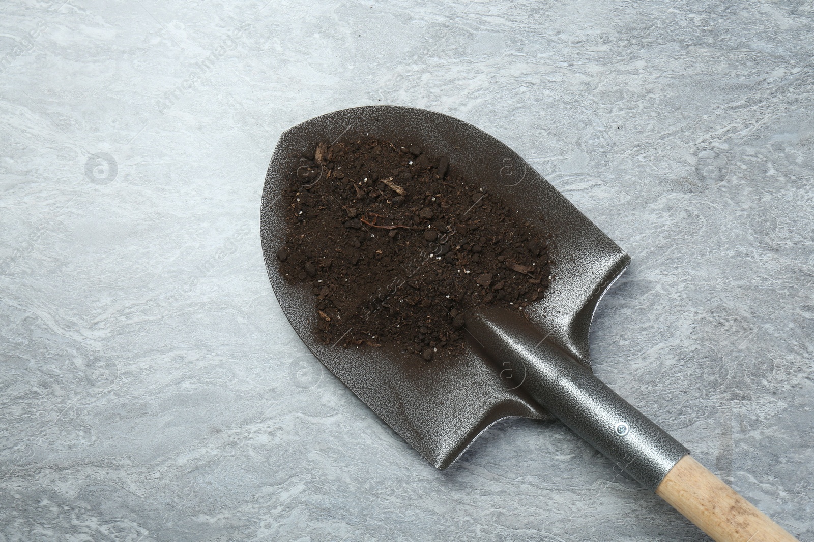 Metal shovel with fertile soil on gray textured surface, top view. Space for text Photo of Metal shovel with fertile soil on gray textured surface, top view. Space for text