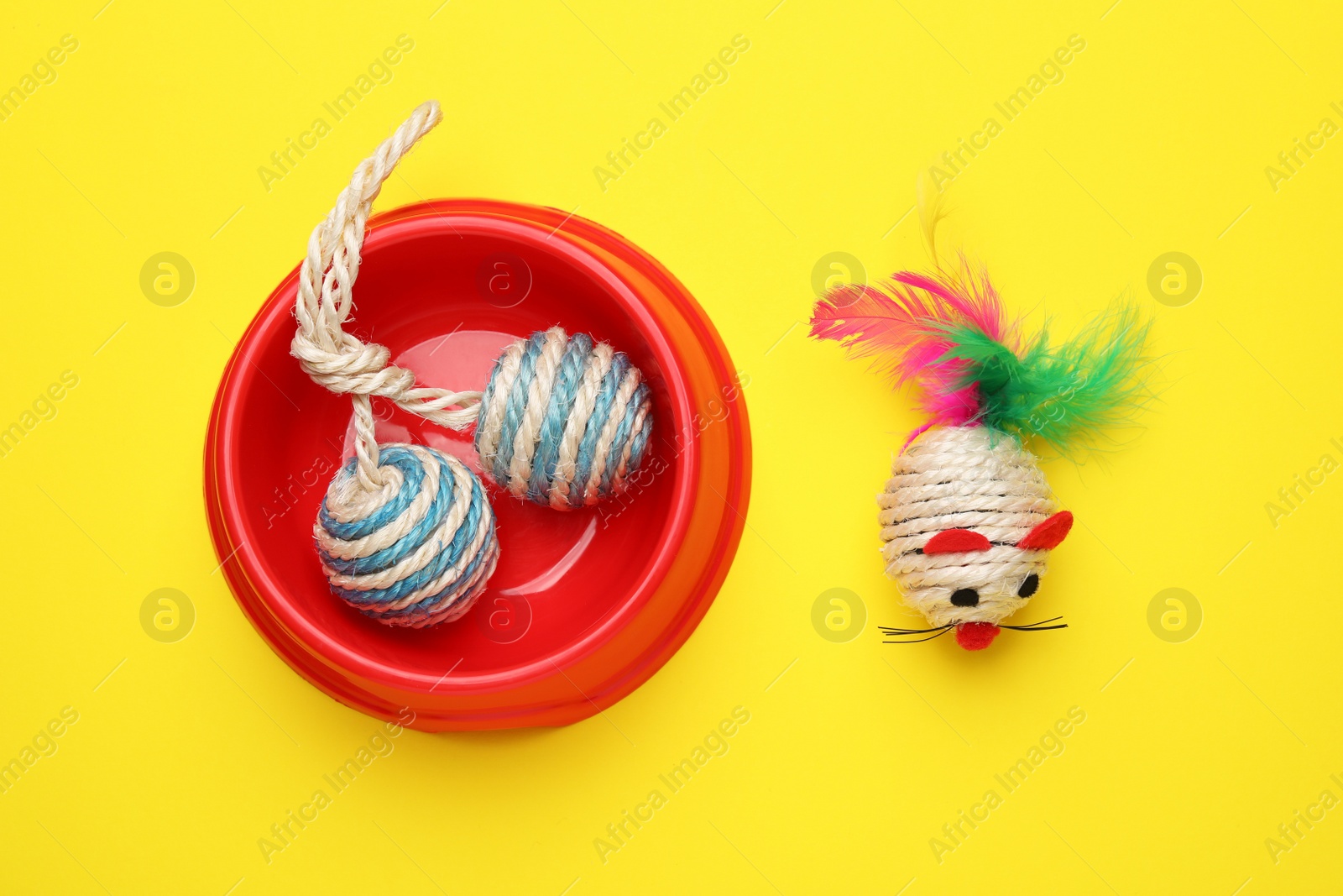 Photo of Pet toys and bowl on yellow background, flat lay