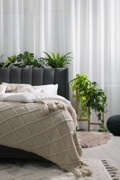 Photo of Comfortable bed with pillows, duvet and beautiful houseplants in bedroom. Interior design