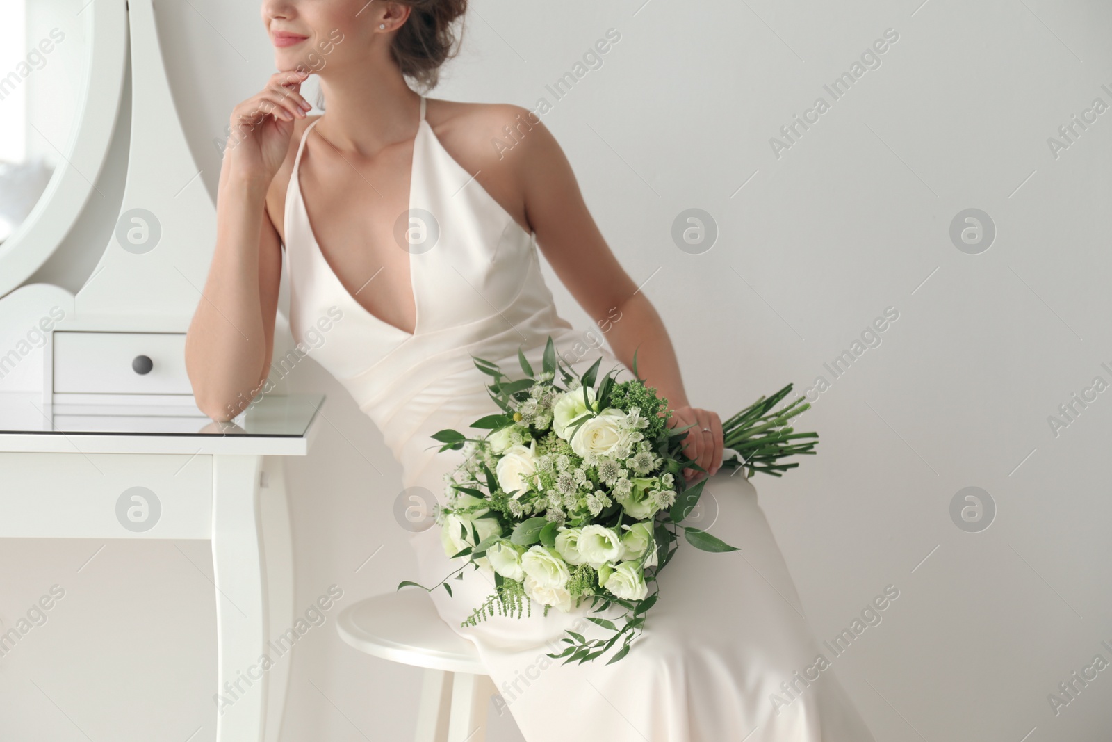 Photo of Young bride wearing wedding dress with beautiful bouquet in room, closeup
