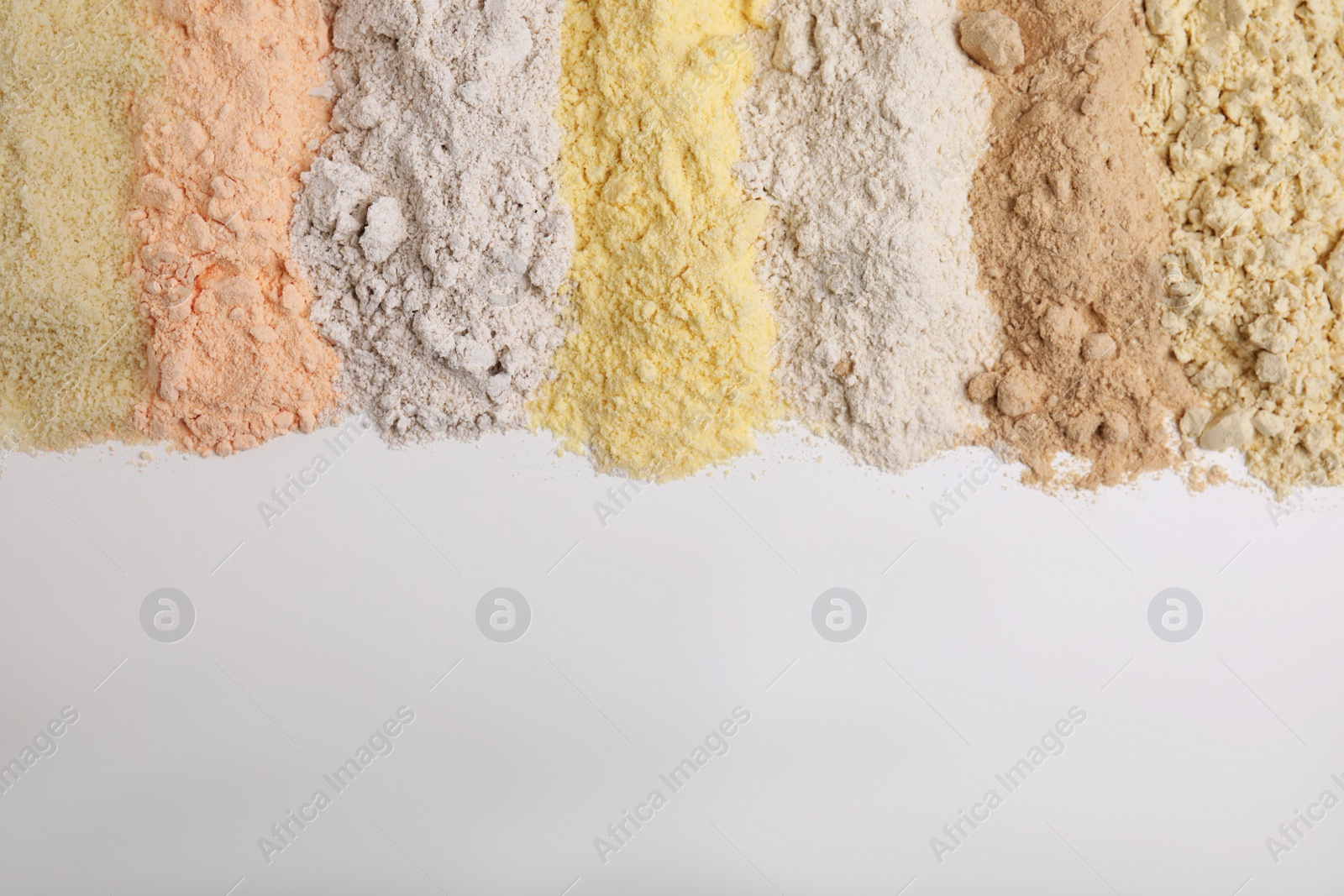 Photo of Different types of flours on white background, flat lay. Space for text