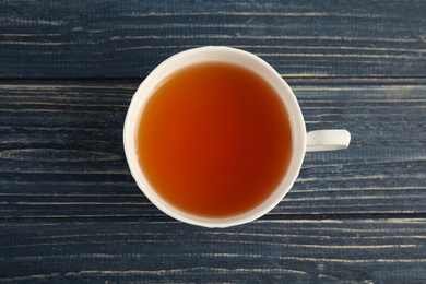 Photo of Cup of delicious tea on wooden background, top view