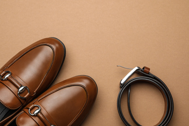 Photo of Pair of stylish male shoes and leather belt on brown background, flat lay