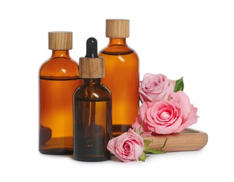 Photo of Bottles of essential rose oil and flowers on white background