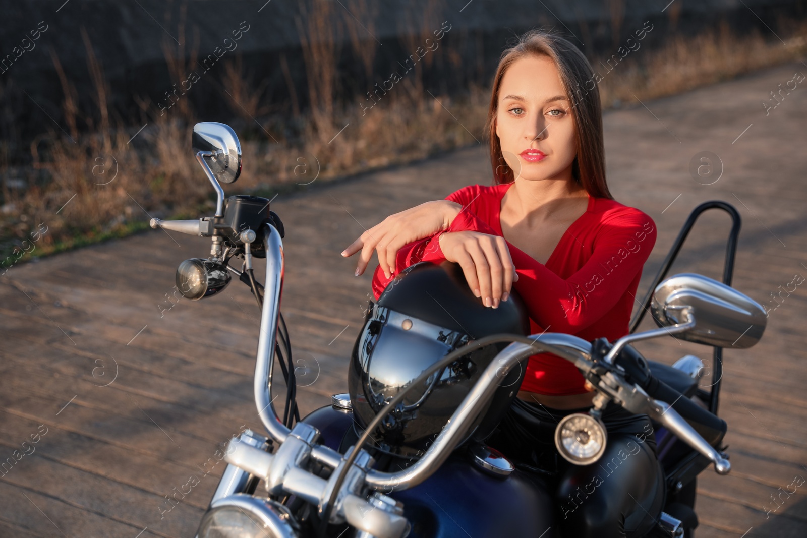 Photo of Beautiful young woman with helmet sitting on motorcycle outdoors