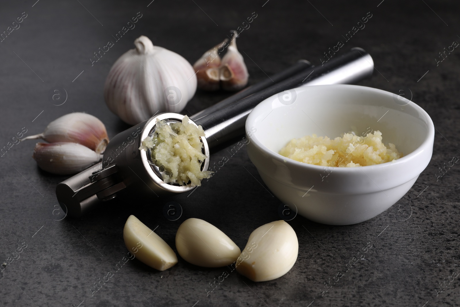 Photo of Garlic press, cloves and mince on grey table, closeup